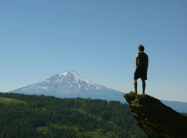 a man standing on a rock looking at a mountain