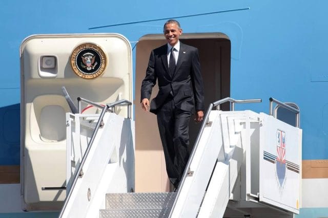 Barack Obama in a suit walking up a flight of stairs