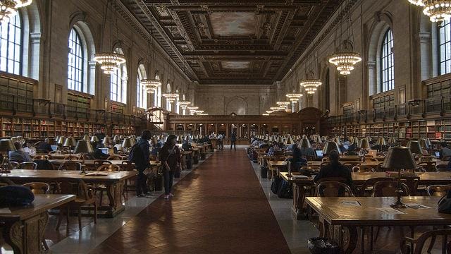 a large room with tables and people with New York Public Library in the background