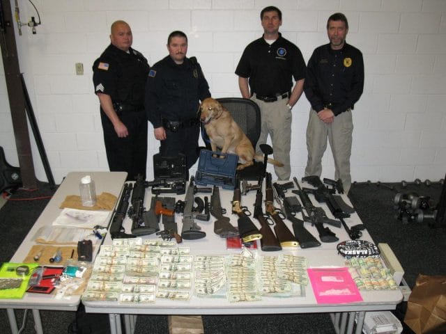 a group of men standing next to a table with a dog on it