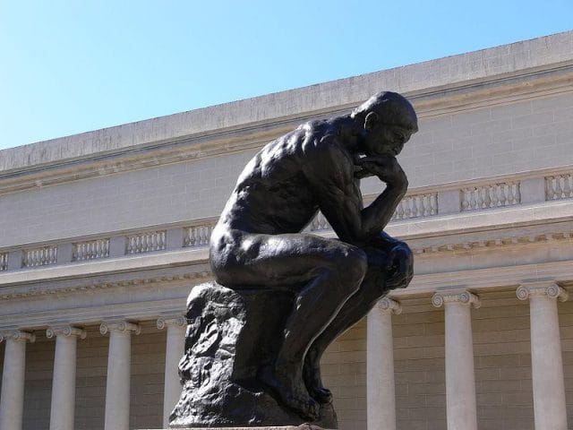 a statue of a man with a horse with Legion of Honor in the background