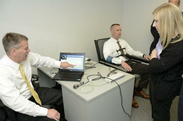 a group of people sitting around a table looking at a laptop