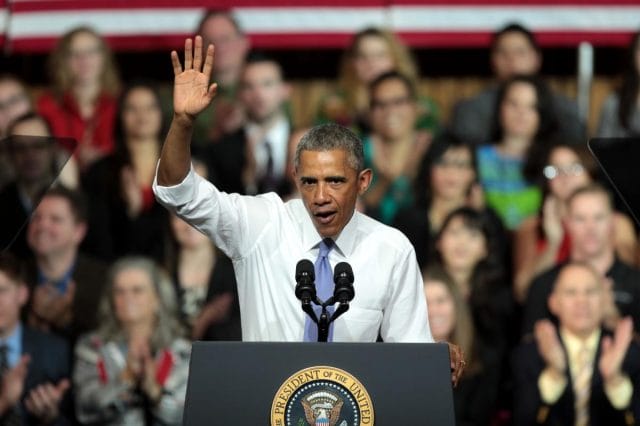 Barack Obama standing at a podium with his hand raised