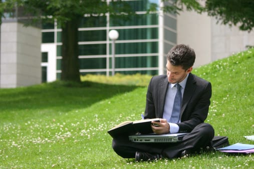 a man sitting on the grass using a laptop