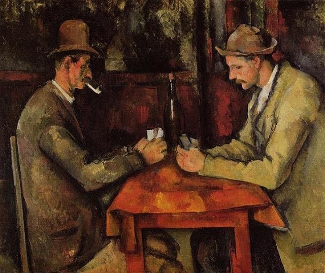 a couple of men sitting at a table with a bottle of alcohol