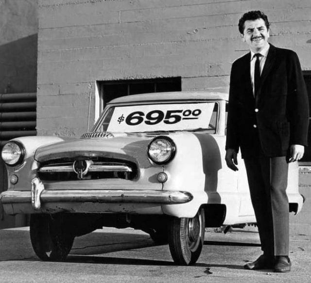 Ernie Kovacs standing next to a car