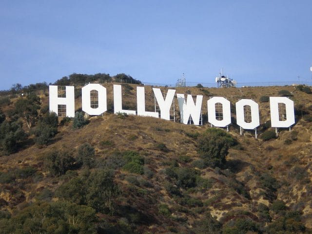 a white sign on a hill with Hollywood Sign in the background