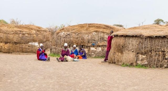 a group of people sitting outside of a hut