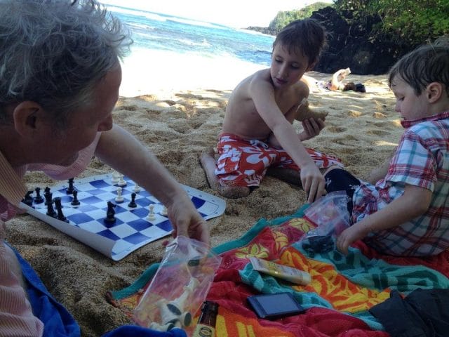 a group of boys playing chess on a beach