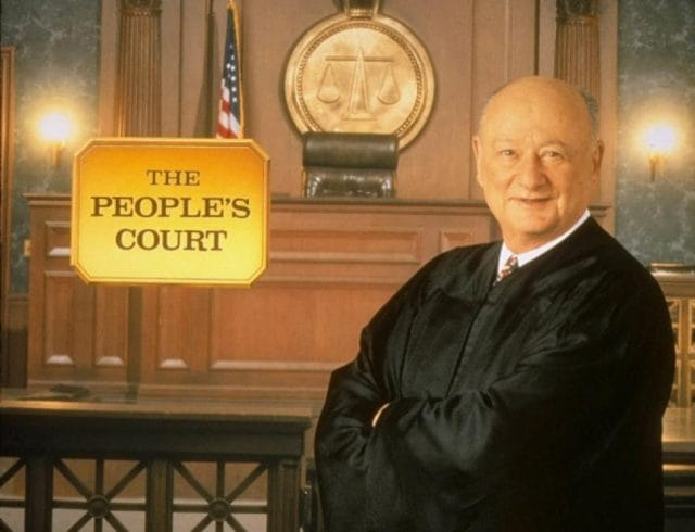 Ed Koch standing in front of a podium with a sign on it