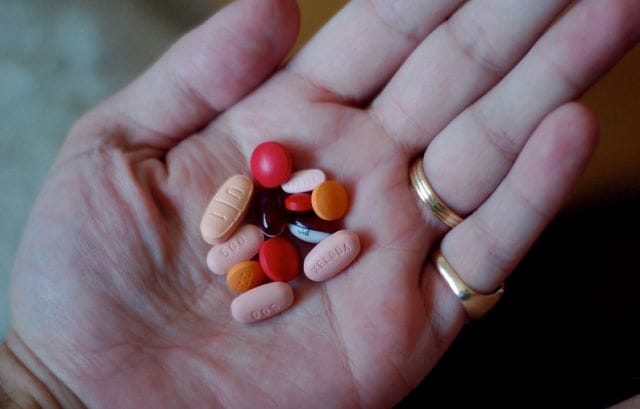 a hand holding a handful of pills