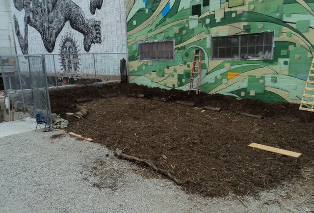 a pile of dirt in front of a building with graffiti on it