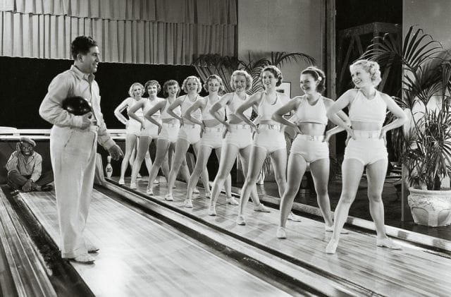 a person standing in front of a group of women in white dresses