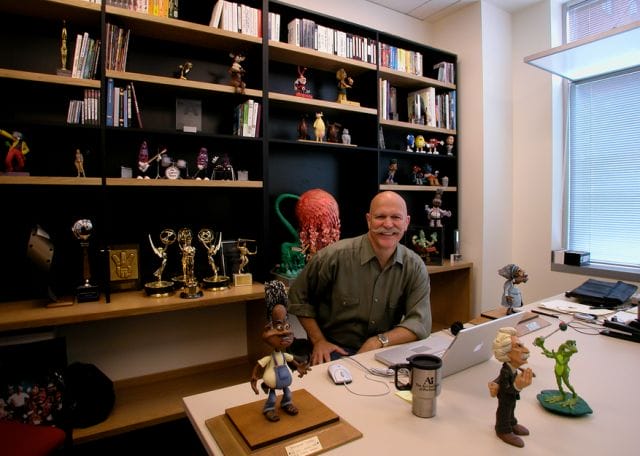 Will Vinton sitting at a desk with a toy figurine