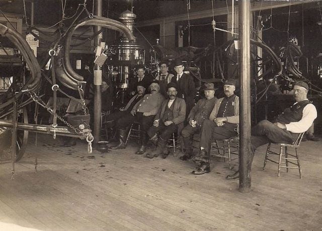 a group of men sitting on stools in a room