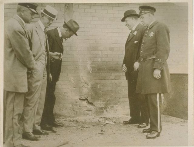 a group of men standing next to a brick wall