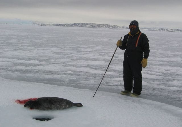a man standing in the snow with a fish