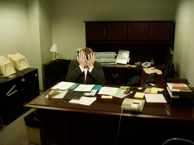 a person sitting at a desk with the head in the hand