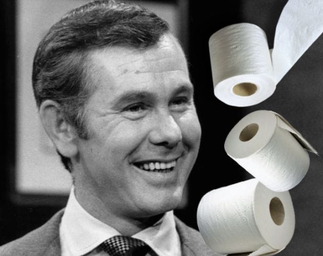 Johnny Carson smiling with a few white objects on his head