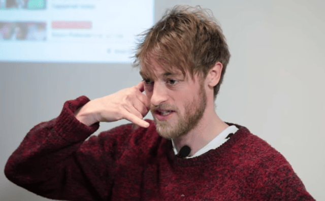 Crispin Freeman with a beard pointing