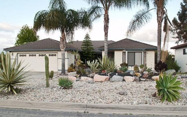 a house with palm trees and rocks
