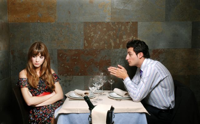 a man and woman sitting at a table with wine glasses