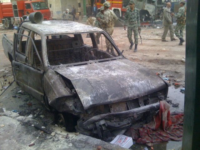a destroyed car with people standing around