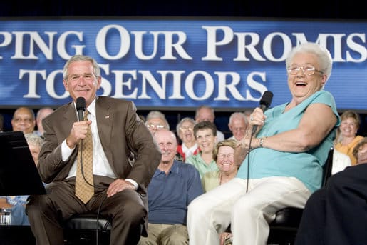 George W. Bush and woman speaking into microphones in front of an audience