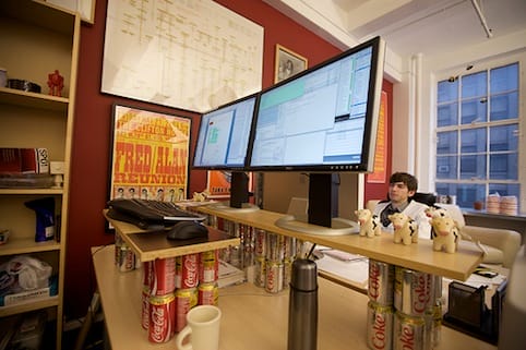 a person sitting at a desk with a computer and other objects