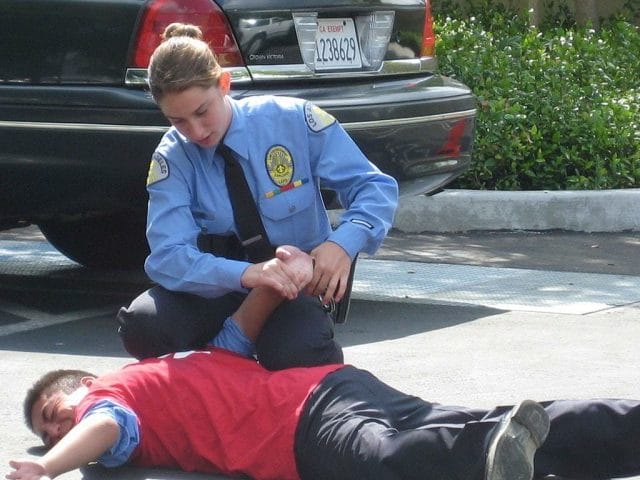 a person in a blue uniform kneeling down next to a person in a red shirt