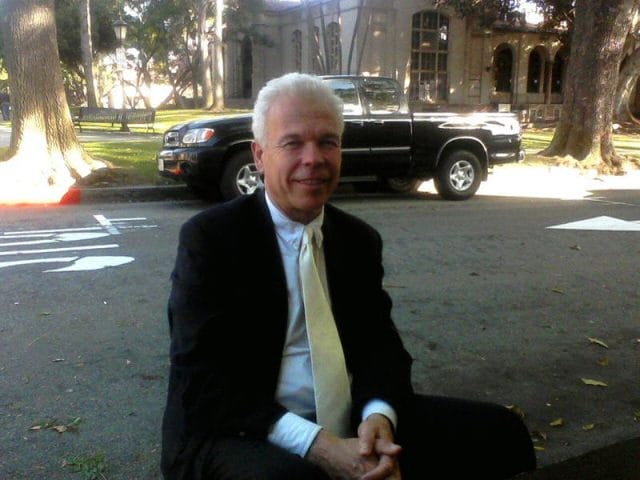 a man in a suit sitting on a sidewalk