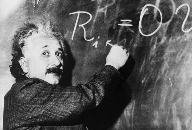 Albert Einstein writing on a chalkboard