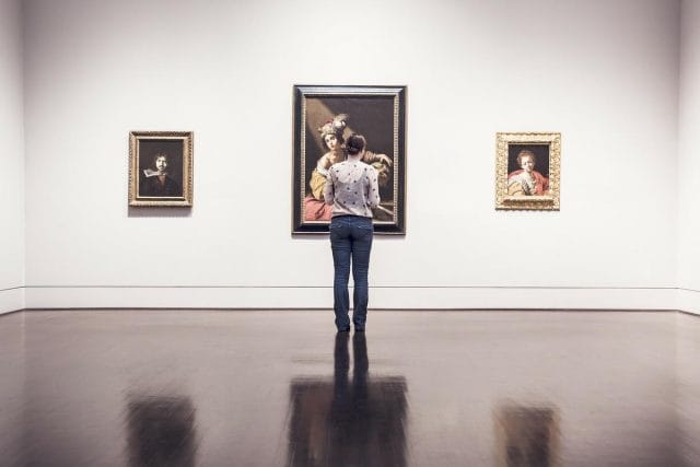 a person standing in front of a wall with paintings on it