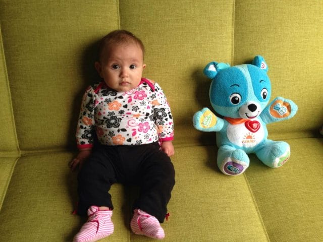 a baby sitting next to a stuffed animal