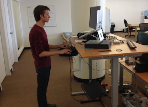 a person standing in front of a desk with a computer