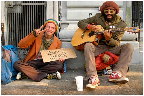 a couple of men sitting on the sidewalk playing guitars
