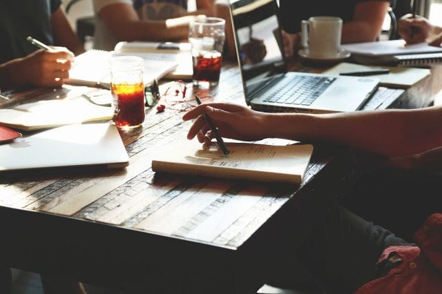 a group of people sitting at a table with papers and a laptop