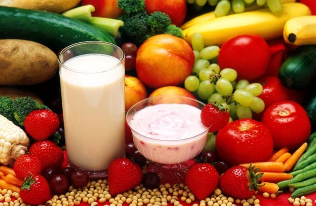 a glass of milk next to a bowl of fruit