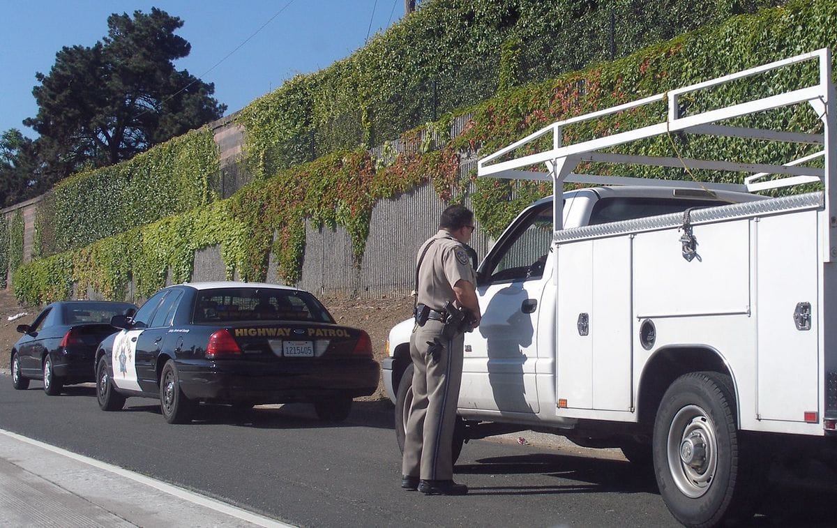 a police officer standing next to a car that is crashed into a truck