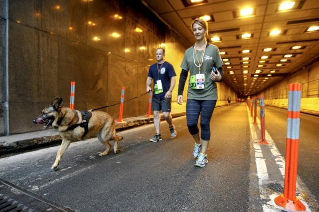 a man and a woman jogging with a dog
