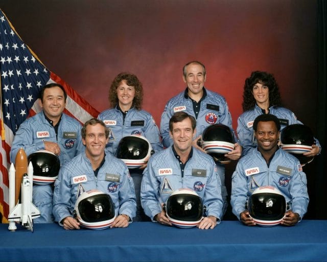 Dick Scobee, Michael J. Smith, Ronald McNair, Ellison Onizuka, Gregory Jarvis, Christa McAuliffe, Judith Resnik wearing helmets