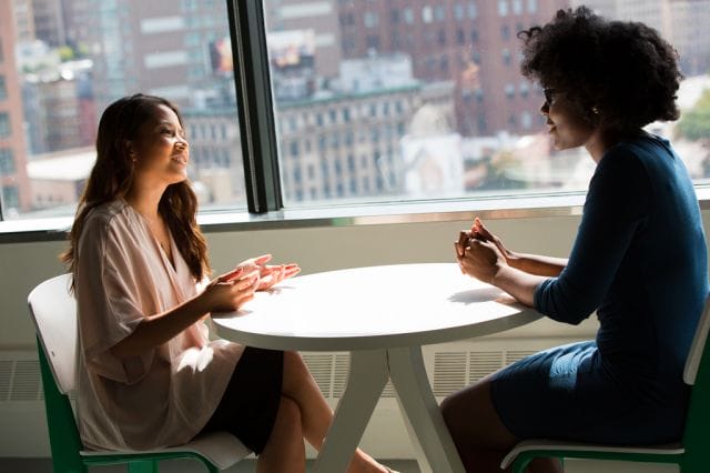 a couple of women sitting at a table with a city view