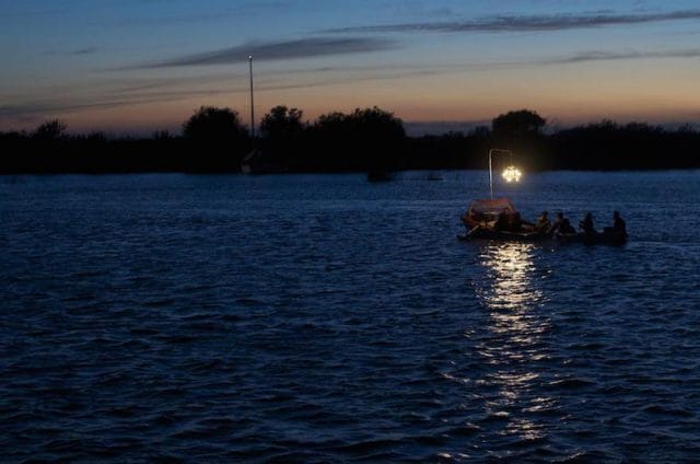 a group of people on a boat in the water at sunset