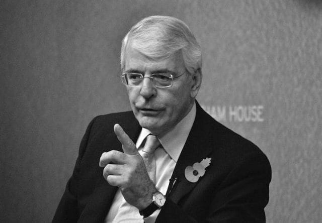 John Major wearing glasses and a suit
