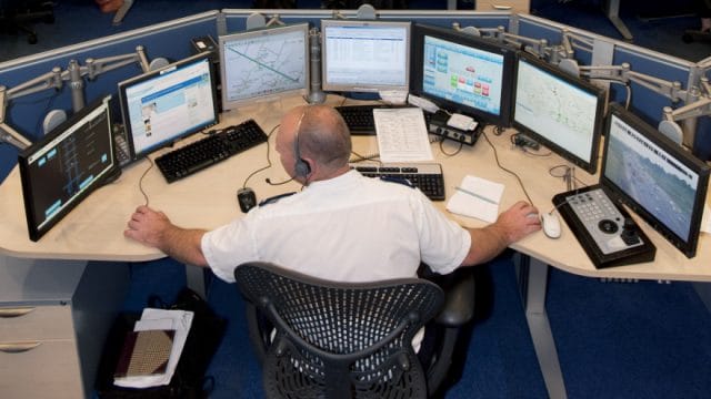 a person sitting at a desk with multiple computers