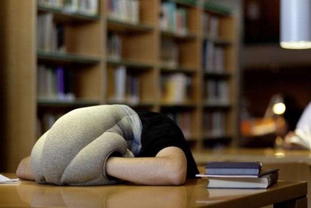 a person's legs on a table in front of a bookshelf