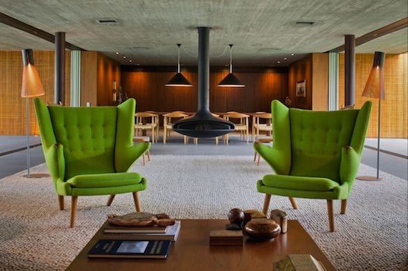 a room with green chairs and a table with a book and a lamp