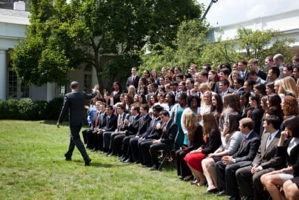 a person walking in front of a group of people sitting on chairs