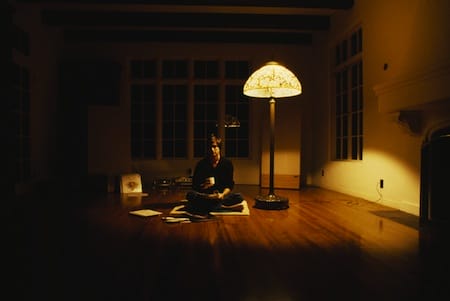 a person sitting on a rug in a room with a lamp and a window