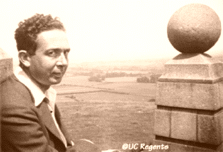 Leo Szilard standing next to a stone wall with a large ball on it